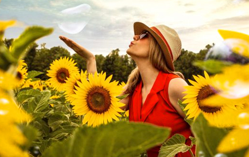 woman blows a kiss into the air among sunflowers